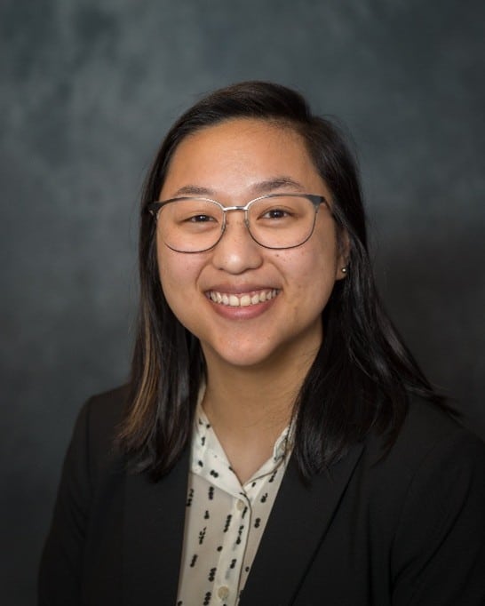 A woman wearing glasses and a suit.